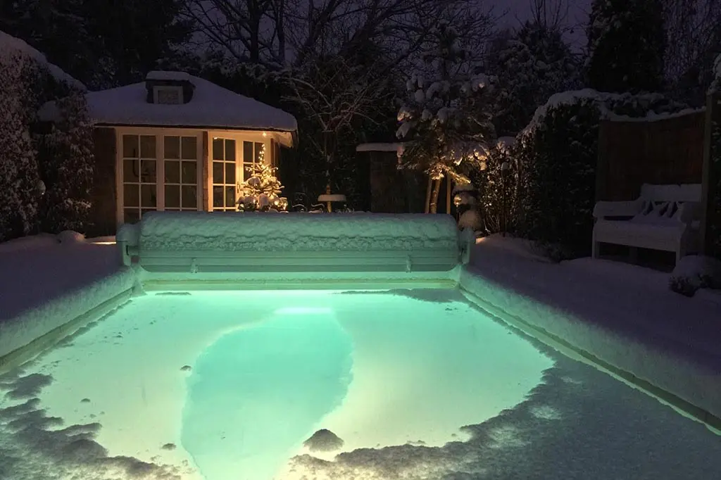 Swimmingpool mit Schnee nachts beleuchtet München
